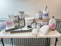 All epoxy containers, mixing cups, pigments, rails and bags displayed on table
