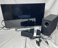 TV, soundbar, subwoofer, remote, mounts and cables displayed together