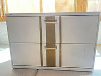 Front view of white metal lateral file cabinet showing gold accent and two drawers