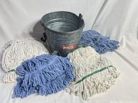 Bucket with four mop heads arranged around it showing overall lot
