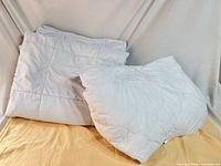 Comforter folded with pillow, showing size and quilted pattern
