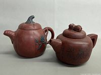 Two signed clay teapots side by side