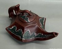 Left side view showing body, spout, lid, painted motif