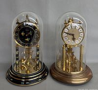 Front view of both glass-domed torsion clocks