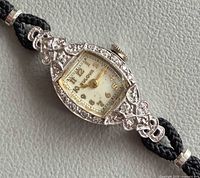 Front view of Bulova watch showing dial, diamond bezel, cord strap