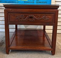 Front view showing carved drawer, shelf and legs