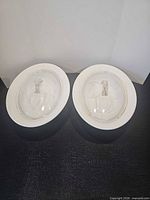 Both white oval CorningWare casseroles with lids side by side