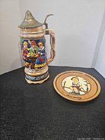 Ceramic beer stein beside wooden plaque front view