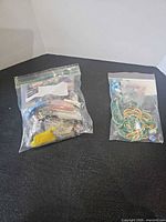 Two resealable plastic bags of assorted beads on black surface