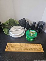 Group shot of all items: binoculars, lantern, mess kit, candle, cribbage board, green pouch