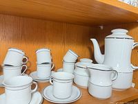 Primary pieces including teapot, sugar, creamer, cups and saucers in white with silver rim