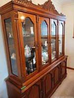 Full view of the two-piece oak china cabinet showing glass doors and carved crown