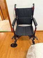 Front view of black Drive transport wheelchair showing seat, armrests and caster wheels