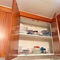 Cabinet with shelves showing plastic containers and glass items
