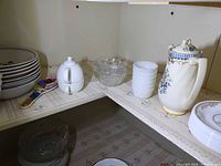 Upper shelf with coffee pot, milk glass tumblers, pressed glass bowl, sugar bowl, spoon rest, stoneware bowls