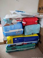 Stacked sealed packs of TENA and Depend XL adult underwear, Huggies baby wipes and other items