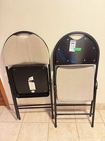 Two folded chairs showing back panels and frames