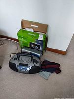 Lot overview showing RCA boom box, Metrosonix radio, Insignia photo frame box and accessories