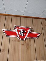 Full view of red white black TC winged logo wall clock mounted on wood panel wall