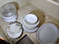 Porcelain dinnerware stacks, crystal bowls, metal serving piece