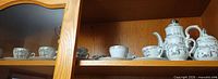 Entire set on cabinet shelf showing cups, saucers, pot, creamer, sugar