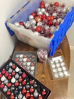 Overall lot with plastic tote full of ornaments, trays, tube and pack on table