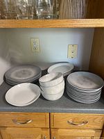 Stacked grey glazed dinner plates, small plates, bowls visible on countertop