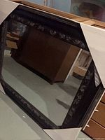 Front view of square mirror with black carved frame in packaging