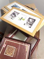 Stack of assorted frames including four light wood collage frames on top of brown/black frames