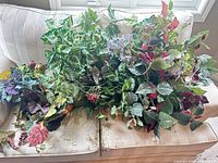 Wide view of assorted artificial greenery and flowers on sofa