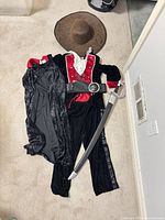 Full costume set laid out showing jumpsuit, cape, belt, hat, sword