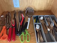 Overview of drawer showing utensils, measuring spoons, tongs, shears, and flatware tray