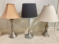 Three table lamps with silver bases and various shades