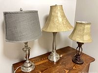 Front view of all three table lamps with shades on wooden surface