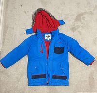 Full view of blue coat with hood and red lining