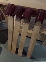 Four red metal sawhorse brackets attached to lumber legs leaning against structure