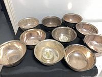 Group of ten silver-plated bowls on black surface