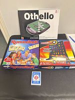 Group shot of Othello, Rummikub, Connect 4 boxes and Bicycle deck