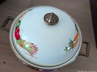 Top view showing domed lid with vegetable motif and brass knob