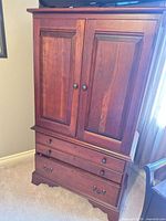 Front view of solid wood armoire showing double doors and three lower drawers