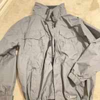 Full view of the grey Wetskins shell jacket laid flat
