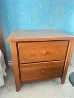 Front view showing entire wooden two-drawer nightstand with knobs