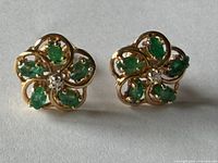 Pair of gold stud earrings with emeralds and diamonds front view