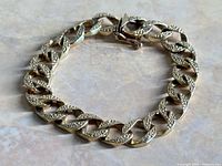 Full view of yellow gold curb link bracelet laid flat