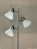 Close-up of two of the three glass shades and chrome arms