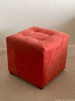 Overall view of cube ottoman showing color, tufting, and shape