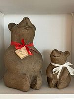 Front view of both clay bear sculptures showing size comparison and ribbons