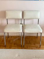 Front view of both chrome and white vinyl dining chairs