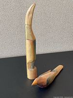 Both wooden bird sculptures standing and lying to show size difference