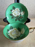 Cup and saucer front view showing rose motif and green colour